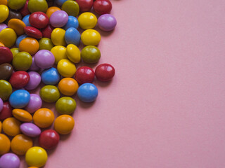 Top view of colorful chocolate candy with copy space. Pink background