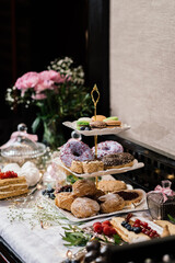 donut in colored glaze multicolored macaroons on a multi-tiered plate next to other desserts