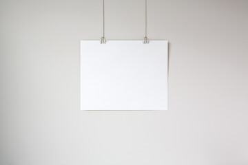 Horizontal hanging poster mockup on a neutral coloured wall. Hanging by clips and string. 4:5...