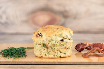 Freshly baked muffin with dill and bacon on a cutting board.