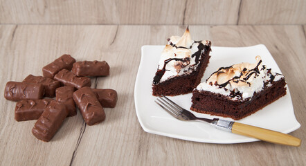Delicious chocolate candies with cake on a wooden background.