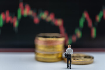 Business Money and Financial Concept. Businessman miniature figure people walking to  stack of gold coins with candlestick chart as background.