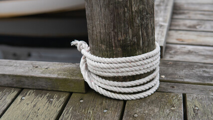 Naklejka premium Many ropes tied to a wooden bridge in the harbor.