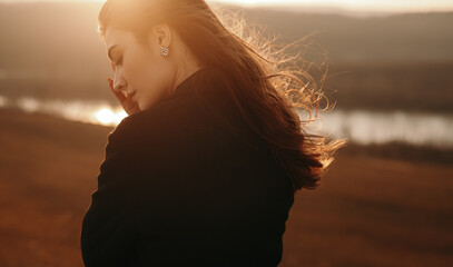 Peaceful woman standing near lake at sundown