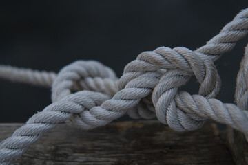 Fototapeta na wymiar A beautiful tied knot in the harbor. White old rope. Strong maritime team work concept.