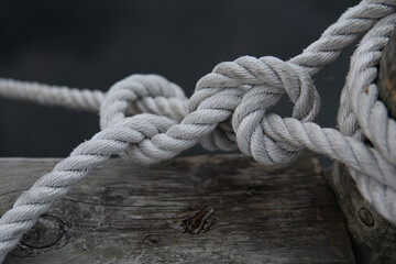 Fototapeta na wymiar A beautiful tied knot in the harbor. White old rope. Strong maritime team work concept.