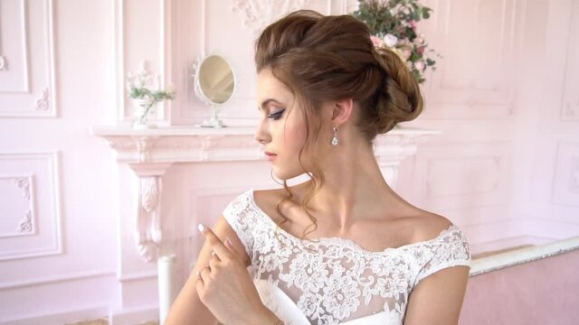 Slow Motion Beautiful Young Model In A White Lace Dress Sits On A White Bed. Gor
