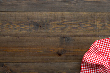 Red picnic cloth on wooden table, top view