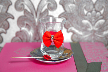 Tea in Azerbaijani traditional armudu pear-shaped glass . Filtered tea for engagement . closed with a red ribbon . check bow tie . Black turkish tea in pear shape glass, aromatic tea in armudu cup .