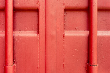 Metal wall with a pipe covered with red paint