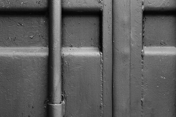 Metal wall with a pipe covered with red paint