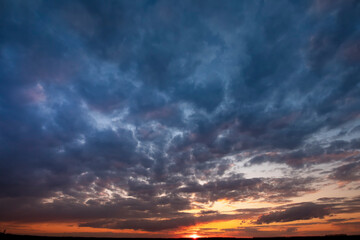 Fototapeta na wymiar Dawn with storm clouds, crimson sky and sunshine.