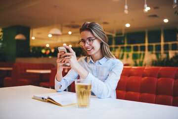 Delighted woman checking social network in cafe