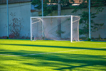 Fototapeta premium Empty white gate on the football field with green grass. Concept of training in football sections and schools, preparation for competitions and matches.
