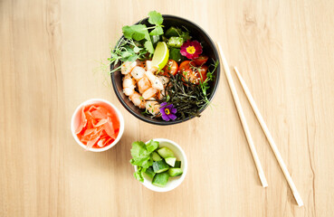 Poke salad with shrimp in a bowl. Ingredients Shrimp, blanched spinach, cherry tomatoes, rice, cucumber, soy-ginger sauce, Spicy sauce, nori, sesame, lime, cilantro. Asian seafood salad concept.