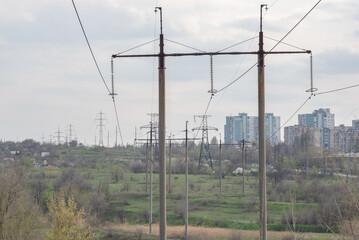 high voltage poles with wires on the background of city houses