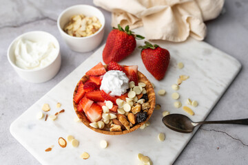 Greek yogurt in ice cream waffle bowl with fruit and nuts, healthy diet friendly dessert. Fruity waffle bowl