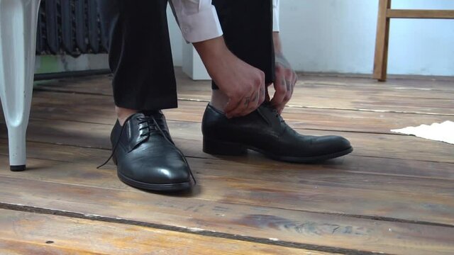 Man ties up his shoelaces on his black shoes