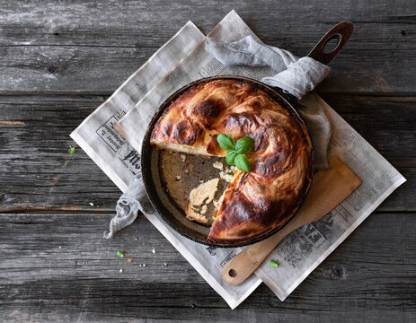 Vertuta. Feta roll pie with basil in a frying pan on an old wooden background. Top view. Flat lay