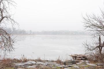 foggy landscape of frozen river with tree branches on the sides of the frame