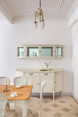 Front view of vintage style dining room with wooden table setting for two persons, tile floor and retro lamps. Refurbished apartment in Barcelona old city