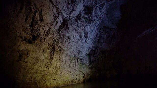 Giant limestone underground cave Pond river water flow reflecting the rocks. Underground karst cave in Slovenia. Tilt up