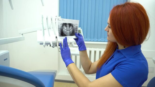 4K Close up female dentist pointing at patient's X-ray image in dental office.