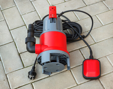 Household submersible pump with plastic housing lies on stone floor