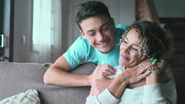 Happy middle age mother spend time with teenager son, relatives people hugging at home, adult attentive millennial grateful child wrapped in a plaid or warm sweater loving mommy caring 