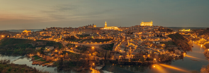 Obraz premium Aerial drone point of view illuminated with night street lights Toledo historical picturesque city of Spain surrounded by Tagus river located on hilltop, evening scene view. Castilla–La Mancha. Spain 