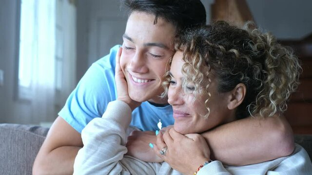 Portrait of middle age mother spend time with teenager son, relatives people hugging at home, adult attentive millennial grateful child wrapped in a plaid or warm sweater loving mommy caring 
