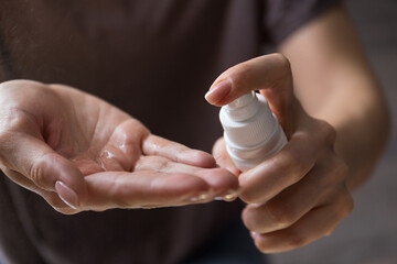 Close up view of woman person using small portable antibacterial hand sanitizer on hands. Coronavirus epidemic prevention concept.