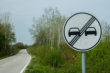 End of No overtaking road traffic sign closeup on country road - obrazy, fototapety, plakaty