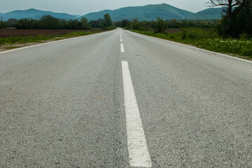 Asphalt surface of country road closeup on countryside landscape background