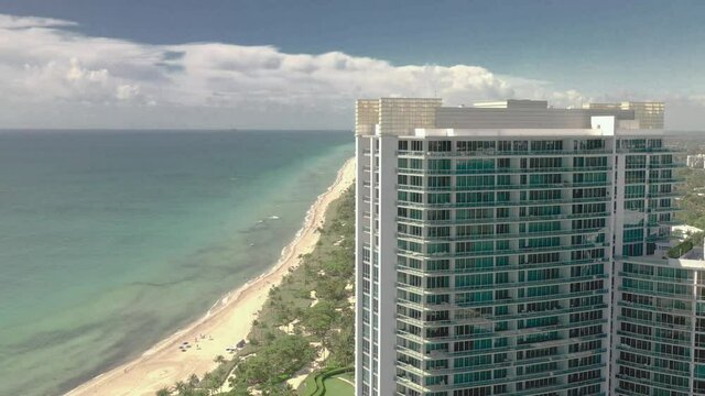 aerial 4k drone footage of a beach appearing behind a hotel building