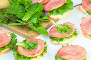 Sandwiches. Cream cheese sandwiches with red fish, baguette, iceberg lettuce leaves, swiss chard on wooden board