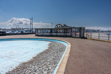 The public paddling pool in Llandudno is emptied and lies abandonded full of pebbles from the beach