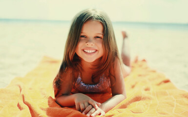 Summer portrait happy smiling child little girl lying on a sand on beach