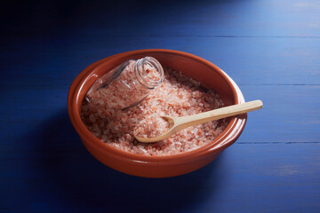 Himalayan salt, pink color, in a red ceramic bowl, on a blue background