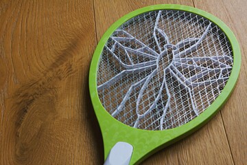 Photo of a insect killer racket in a wooden background.