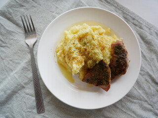 Roasted turkey and mashed potatoes on a white plate, fork on the side on an olive tablecloth