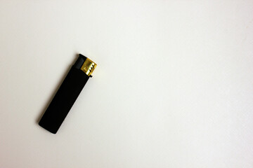 Black plastic gas lighter. A gas lighter, isolated on a white background. The lighter is swollen on the left. View from above. Copy space