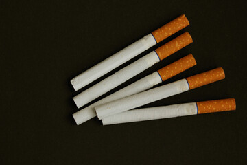 Lots of cigarettes on black background. The concept of World No Tobacco, Tobacco and Lung Health. Copy space. Harm to health. It is bad habit. View from above. Cigarettes with yellow filter are whole.