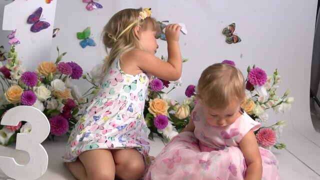 Slow Motion Two little girls in dresses in room with flowers.