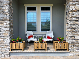 A cozy peaceful front porch of a house with adirondack chairs and flower planters