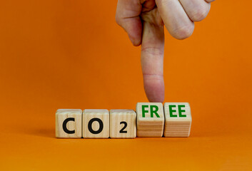 CO2 free symbol. Businessman turns cubes, changes concept words 'CO2' to 'CO2 free'. Beautiful orange table, orange background. Business and CO2 free concept. Copy space.