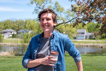 Obraz premium Young guy with takeout coffee in the backyard