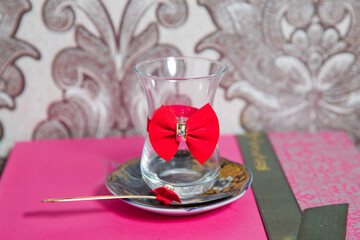 Tea in Azerbaijani traditional armudu pear-shaped glass . Filtered tea for engagement . closed with a red ribbon . check bow tie . Black turkish tea in pear shape glass, aromatic tea in armudu cup .