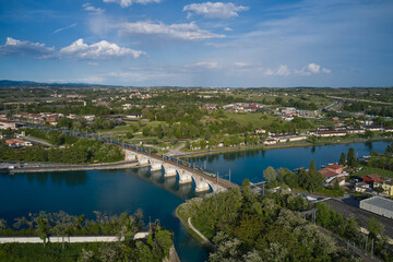 Panoramic aerial view of the train passing over the railway bridge over the river. Peschiera del Garda, Italy. Aerial view of the resort town on Lake Garda.