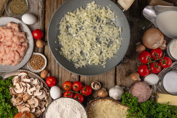 Fototapeta premium Risotto with mushrooms. Cooking process. On a wooden table, ingredients: tomatoes, eggs, rice, mushrooms, herbs, spices. Bright, contrasting colors. Daylight, top view, close-up